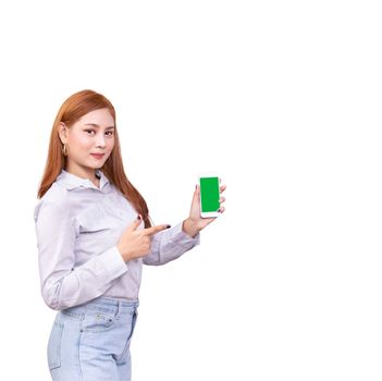 smiling Asian woman standing in casual shirt holding mobile phone and  pointing on smartphone isolated on white background with clipping path