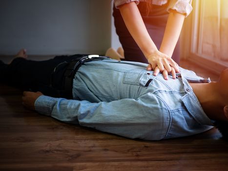 volunteer office woman use hand pump on chest for first aid emergency CPR on heart attack man unconscious, try to resuscitation patient man at work