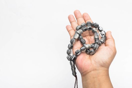 Hand holding muslim beads rosary or tasbih isolated on white background. Selective focus.