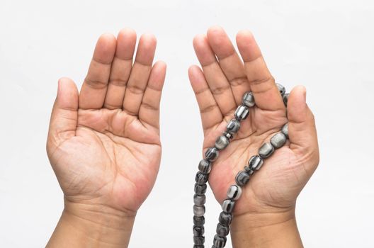 Hand holding muslim beads rosary or tasbih isolated on white background. Selective focus.