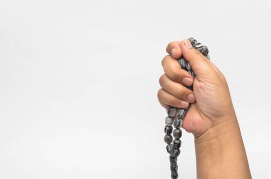 Hand holding muslim beads rosary or tasbih isolated on white background. Selective focus.