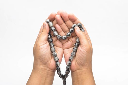 Hand holding muslim beads rosary or tasbih isolated on white background. Selective focus.