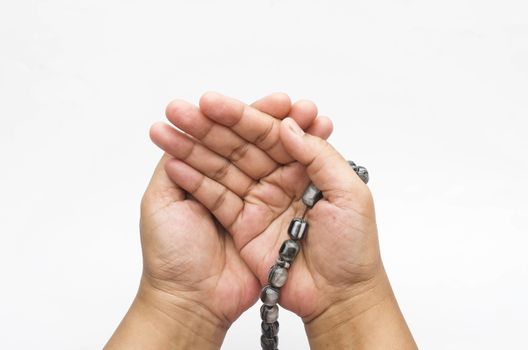 Hand holding muslim beads rosary or tasbih isolated on white background. Selective focus.