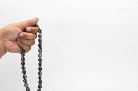 Hand holding muslim beads rosary or tasbih isolated on white background. Selective focus.