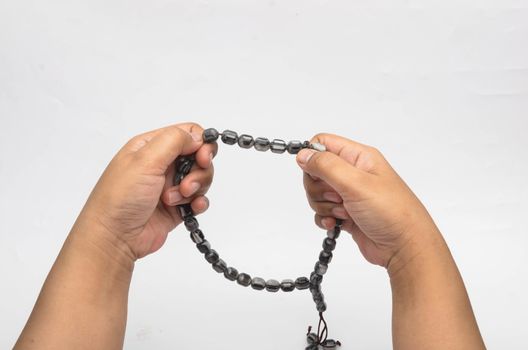 Hand holding muslim beads rosary or tasbih isolated on white background. Selective focus.