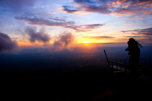 shadow of a woman standing to see the fog and the sunrise in the morning.