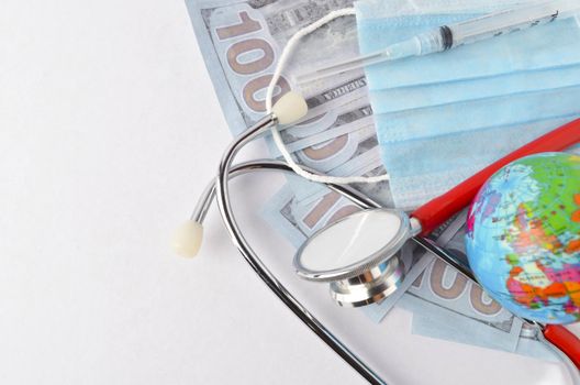 Medical face mask, stethoscope, syringe, world globe and banknotes on white background. Medical concept. Selective focus.