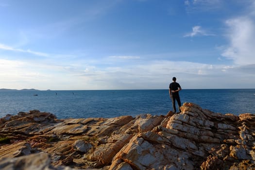 One man put his hand behind him. And make a fight symbol on the rock by the sea at Khao Laem Ya, Rayong, Thailand