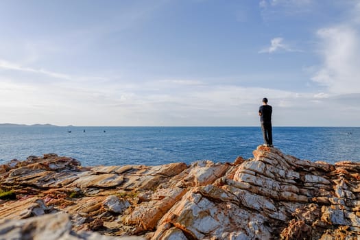 man stood and folded his arms and stood watching the view at Khao Laem Ya, Rayong, Thailand.