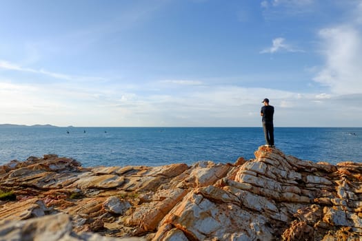 man stood and folded his arms and stood watching the view at Khao Laem Ya, Rayong, Thailand.