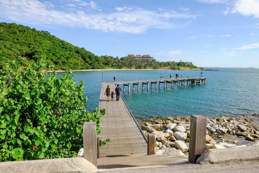 Family holiday with parents carrying children along the sea-side bridge at Khao Laem Ya National Park, Rayong, Thailand.