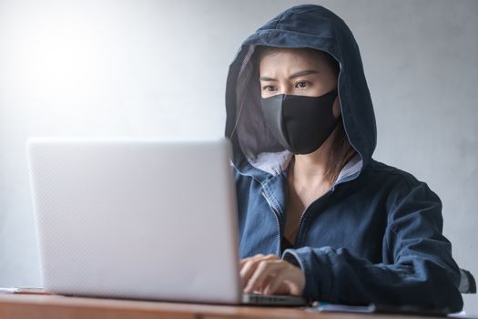 Professional hacker young women Wearing a blue robe with a hood Stealing data from online computer systems By releasing viruses into the system By using laptops and keyboards in older buildings, the concept of malware and hacker