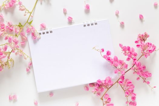 flat lay of white blank calendar with copy space decorate with pink flower isolated on white background