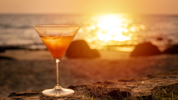 cocktail glass with sea beach view at background during on sunset time