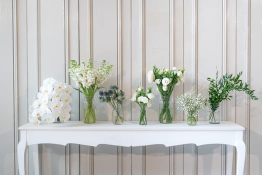 simply composition of different white flower in vase on white vintage table