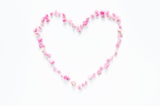 flat lay of floral heart made from pink flowers isolated on white background, top view. flower creative composition