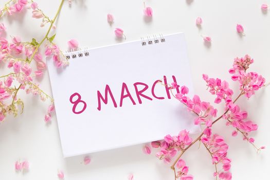 International Women's Day. flat lay of blank calendar with the words "March 8" decorate with pink flower isolated on white background