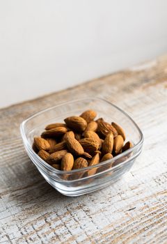 Almonds in a small plate on a vintage wooden table. Almond is a healthy vegetarian protein nutritious food. Natural nuts snacks