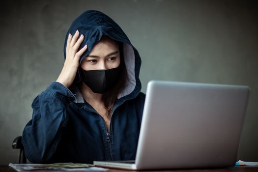 Professional hacker women Wearing a blue shirt with a hood Stealing data from online computer systems By releasing viruses into the system By using laptops and keyboards concept of malware and hacker