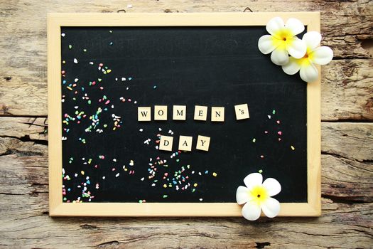 women's day concept. text women's day from wooden block on chalkboard, decorate with flower