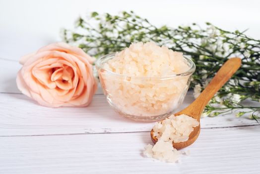 natural skincare concept. organic cosmetic with pink rose salt spa in glass bowl and wood spoon decorate with pink rose and white flower