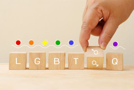 LGBTQ on wooden cube with hand pick gender symbol.