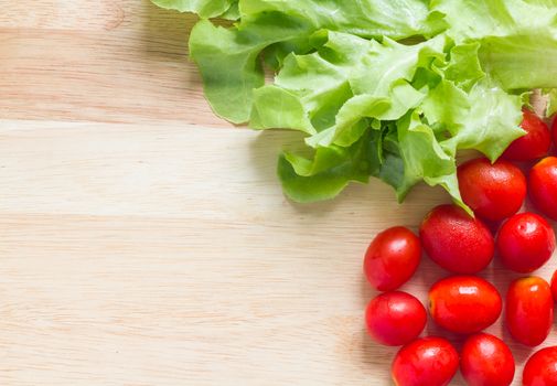 Fresh green oak leaf and cherry tomatoes on wooden background