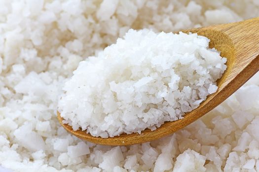 Close up white sea salt on wooden spoon 