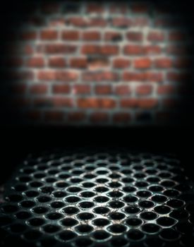 metal perforated table surface in a dark basement against a brick wall close up horror background