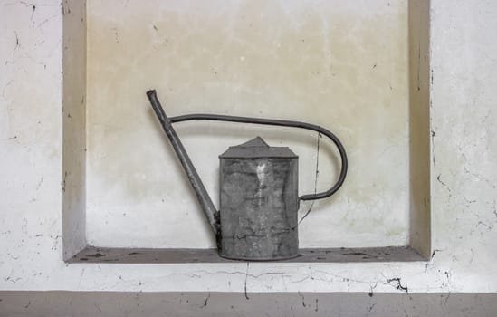 Old watering can abandoned and covered with cobwebs