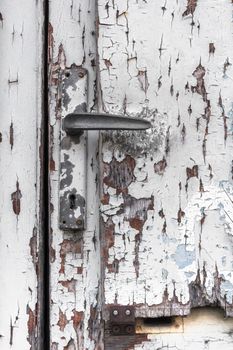 Detail of wooden white door with peeled paint