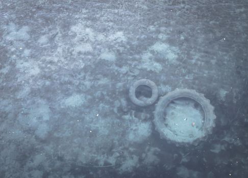 Polluted shallow river with tires under water. Environmental problem.