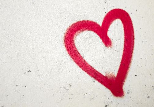 Concept or conceptual painted red abstract heart shape love symbol, dirty wall background, metaphor to urban and romantic valentine, grungy style.