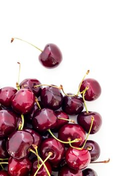 Fresh red cherries on a white surface, seen from above, with blank space.