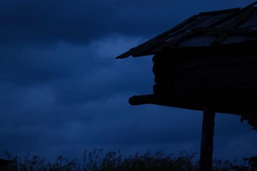 A house on stilts on the shore of the lake. Evening, twilight.