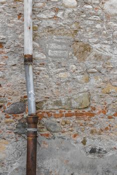 Detail of a downpipe against a brick wall.