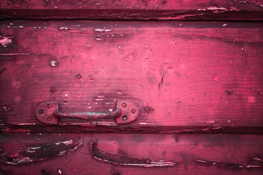 Close-up of a rusty handle on an old red door.