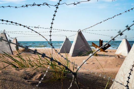 barbed wire and concrete military fence on the beach near the sea in Crimea Ukraine