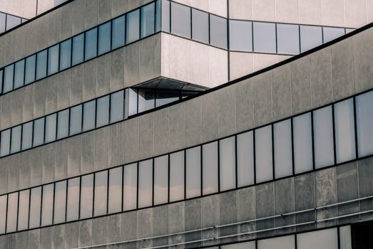 high concrete building with reflection of the sky and clouds in the windows