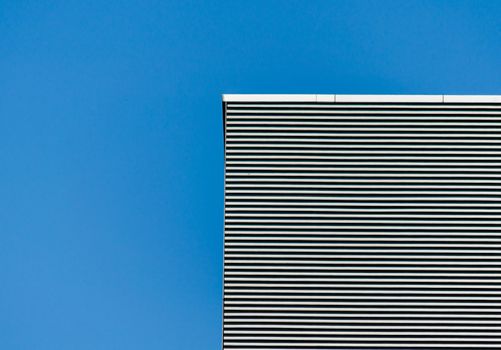 striped wall of a gray tall building against a blue sky