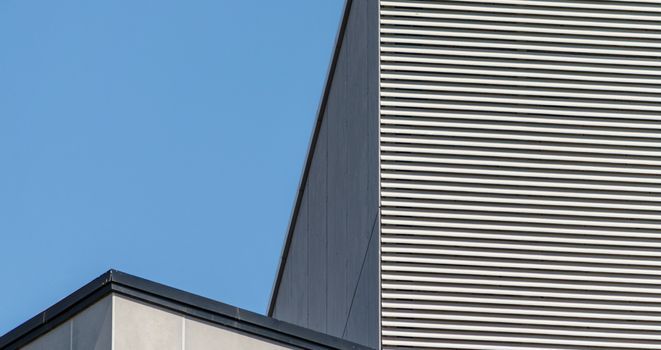 striped wall of a gray tall building against a blue sky