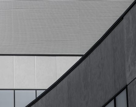 fragment of gray concrete building with a striped wall and empty windows closeup