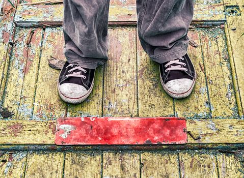 legs of a man in old dirty shoes on a yellow wooden floor close up