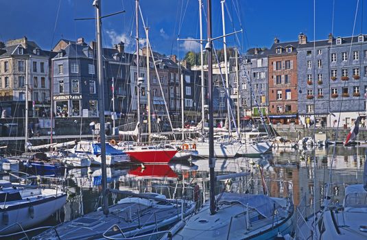HONFLEUR, NORMANDY, FRANCE. JUNEThe harbor in the Northern French town of Honfleur a popular holiday and yachting destination. The inner harbor with fishing boats, yachts, holiday visitors and the unusual architecture of the tall buildings in a busy and colorful setting.