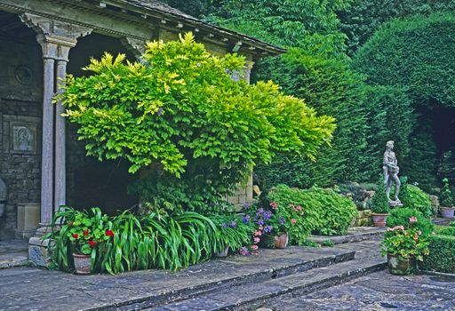 THE CLASSICAL PRAVILION AND GAREN IN THE IFORD MANOR GARDENS, BRADFORD-ON-AVON, WILTSHIRE, ENGLAND. JULY  The classical pravilion with statuary and planted border and continers in Grade 1 listed garden designed by Harold Peto.