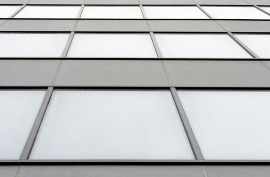 fragment of the wall and windows of a modern tall office building without people  abstract architectural monochromatic background