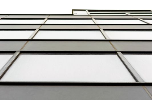 fragment of the wall and windows of a modern tall office building without people abstract architectural monochromatic background