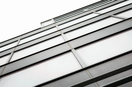 fragment of the wall and windows of a modern tall office building without people abstract architectural monochromatic background