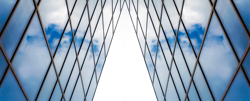 reflection of blue sky with white clouds in a window of a tall office building abstract architectural background