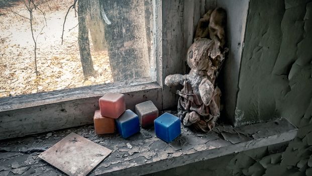 old toy and colored dusty cubes on a windowsill in an abandoned house in Chernobyl Ukraine